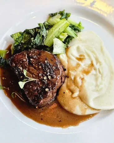 Seared filet mignon with creamy mashed potatoes, sautéed greens and rich pan sauce at Nola Eatery & Bar in Leslieville, Toronto.
