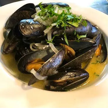 Steamed mussels in white wine, garlic and butter broth topped with fresh parsley at Nola Eatery & Bar in Leslieville, Toronto.