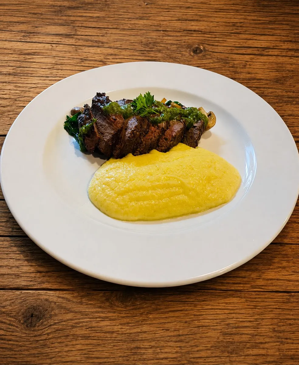 Sirloin steak served with creamy polenta, sautéed mushrooms and green herb sauce at Nola Eatery & Bar in Leslieville, Toronto